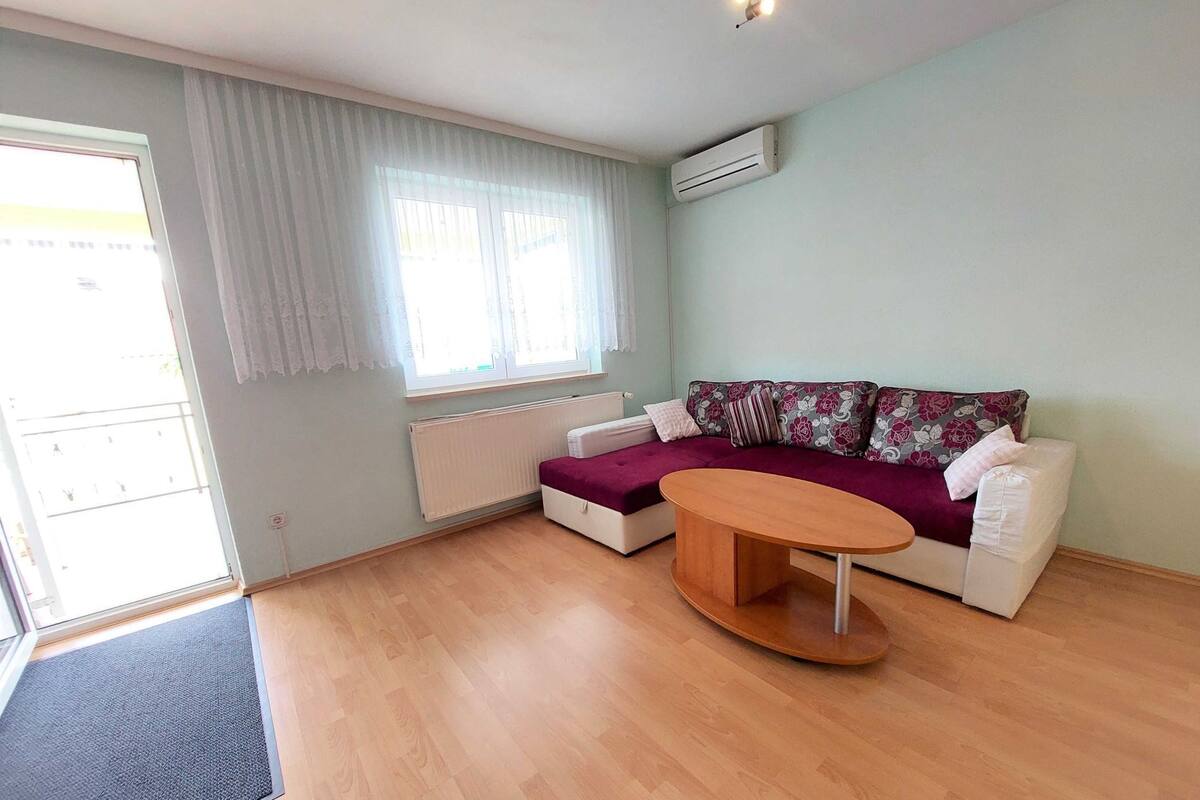 A modern living room with a sofa, a coffee table, and a window with curtains.