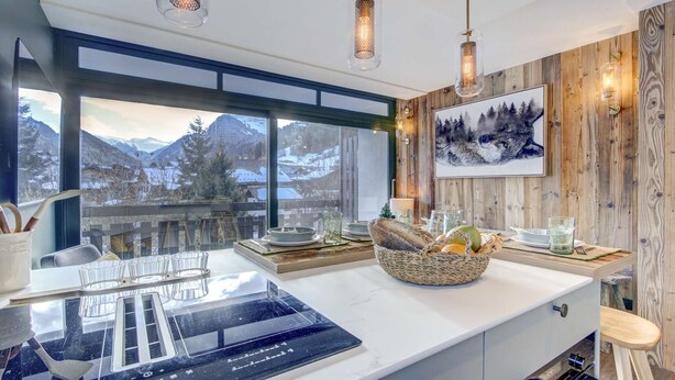 Una cocina moderna con una isla grande, detalles de madera y una vista panorámica a las montañas.