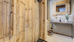 Una pared de madera con diseño rústico, una consola con objetos decorativos y un espejo con marco de madera.