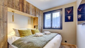 Un dormitorio con cabecera de madera, un ventanal grande y una obra de arte en la pared.