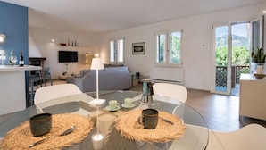 A modern living space with a kitchen, dining area, and a balcony with a mountain view. - Villa Dei Pini, Porto Azzurro (Porto Azzurro)