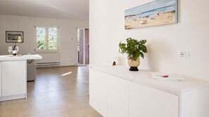A spacious room with a white cabinet, a painting of a beach, and a potted plant. - Villa Dei Pini, Porto Azzurro (Porto Azzurro)