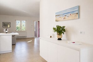 A spacious room with a white cabinet, a painting of a beach, and a potted plant.