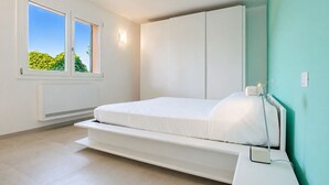 A bedroom with a bed, a window, a wall-mounted heater, and a power outlet. - Villa Dei Pini, Porto Azzurro (Porto Azzurro)
