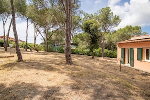 Il s’agit d’une propriété comprenant une zone herbeuse et aride, plusieurs arbres et un bâtiment doté de volets verts.
