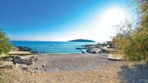 A rocky beach with pebbles and a clear view of the sea and a distant island.