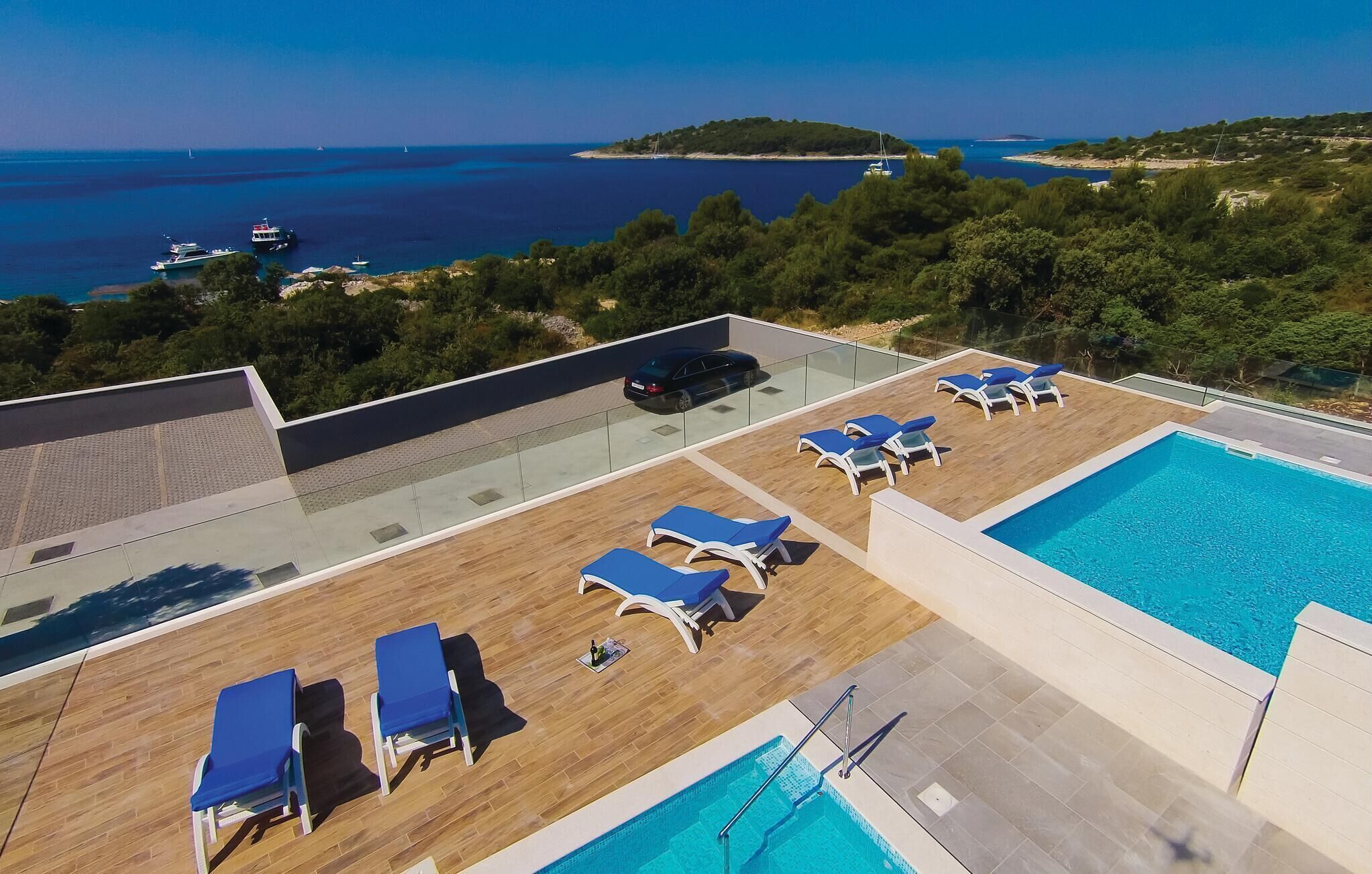 A rooftop pool area with lounge chairs and a view of the sea.