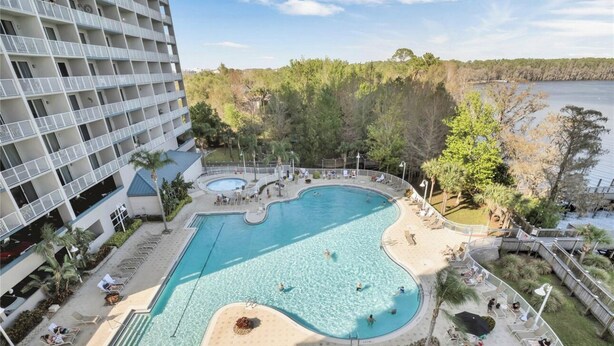 A large outdoor swimming pool with a unique shape, surrounded by lounge chairs and palm trees. - Newly Renovated! 2-Bedroom 2-Bath Stunning LakeView at Blue Heron Beach Resort (Orlando)