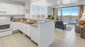 A modern kitchen with white cabinets, a large island, and a dining area with a view. - Newly Renovated! 2-Bedroom 2-Bath Stunning LakeView at Blue Heron Beach Resort (Orlando)