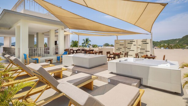 An outdoor lounge area with sun loungers, a large umbrella, and a pool table. - Hotel Tepalcates (San Patricio Melaque)