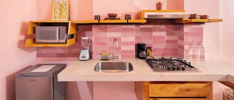 Una cocina compacta equipada con microondas, licuadora, cafetera y estufa a gas.