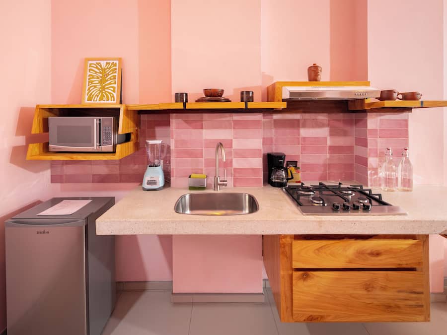 A compact kitchen with a microwave, blender, coffee maker, and gas stove.