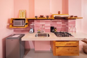 A compact kitchen with a microwave, blender, coffee maker, and gas stove. - Hotel Tepalcates (San Patricio Melaque)