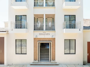 Un hotel llamado 'TEPALCAITES' con una fachada moderna, varios balcones y una entrada central con una escalera.