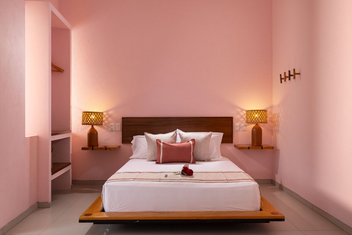 A bedroom with a bed, bedside lamps, and a wooden headboard.