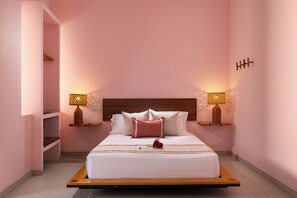 A hotel room with a bed, bedside lamps, a wooden headboard, and a rose on the bed. - Hotel Tepalcates (San Patricio Melaque)