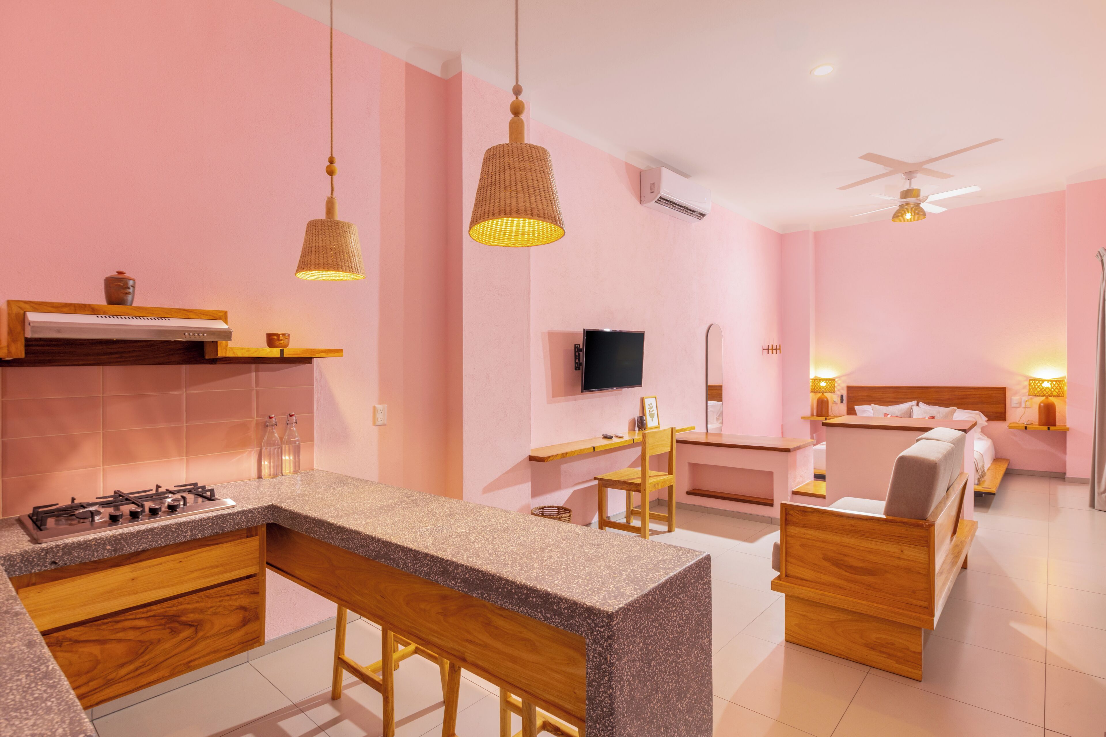 Una cocina moderna con barra, una mesa de comedor y un dormitorio con cama y mesita de noche.