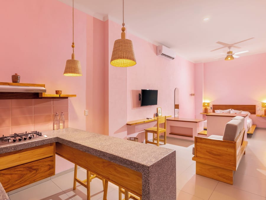 A modern kitchen with a bar area, a dining table, and a bedroom with a bed and bedside table.
