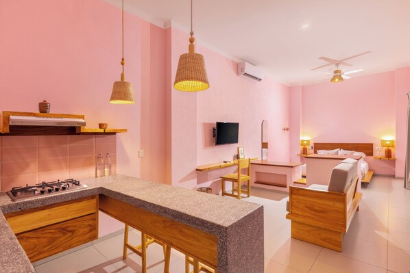 A modern kitchen with a bar area, a dining table, and a bedroom with a bed and bedside table. - Hotel Tepalcates (San Patricio Melaque)