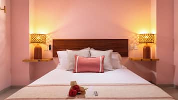 A hotel room with a large bed, two bedside lamps, a wooden headboard, and a bedside table with a lamp.