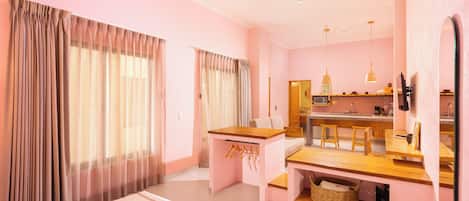 A hotel room with a bed, a desk, a kitchenette, and a bathroom.