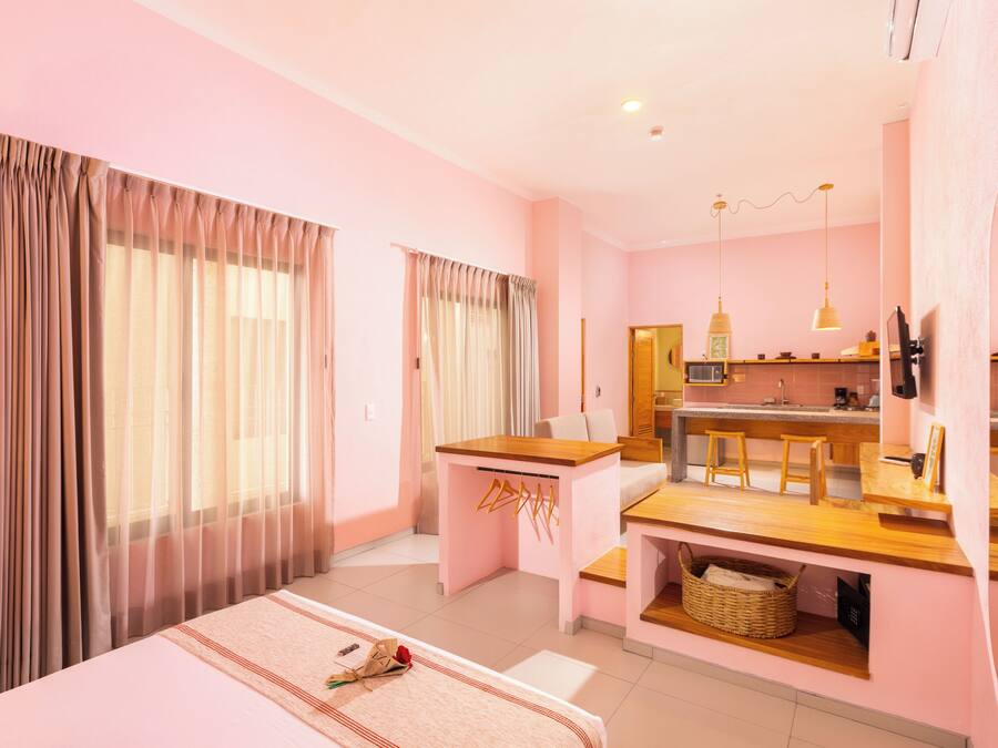 A hotel room with a bed, a desk, a kitchenette, and a bathroom.