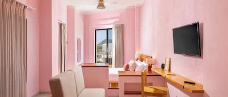 A room with a bed, a desk, a chair, a television, and a window with curtains.