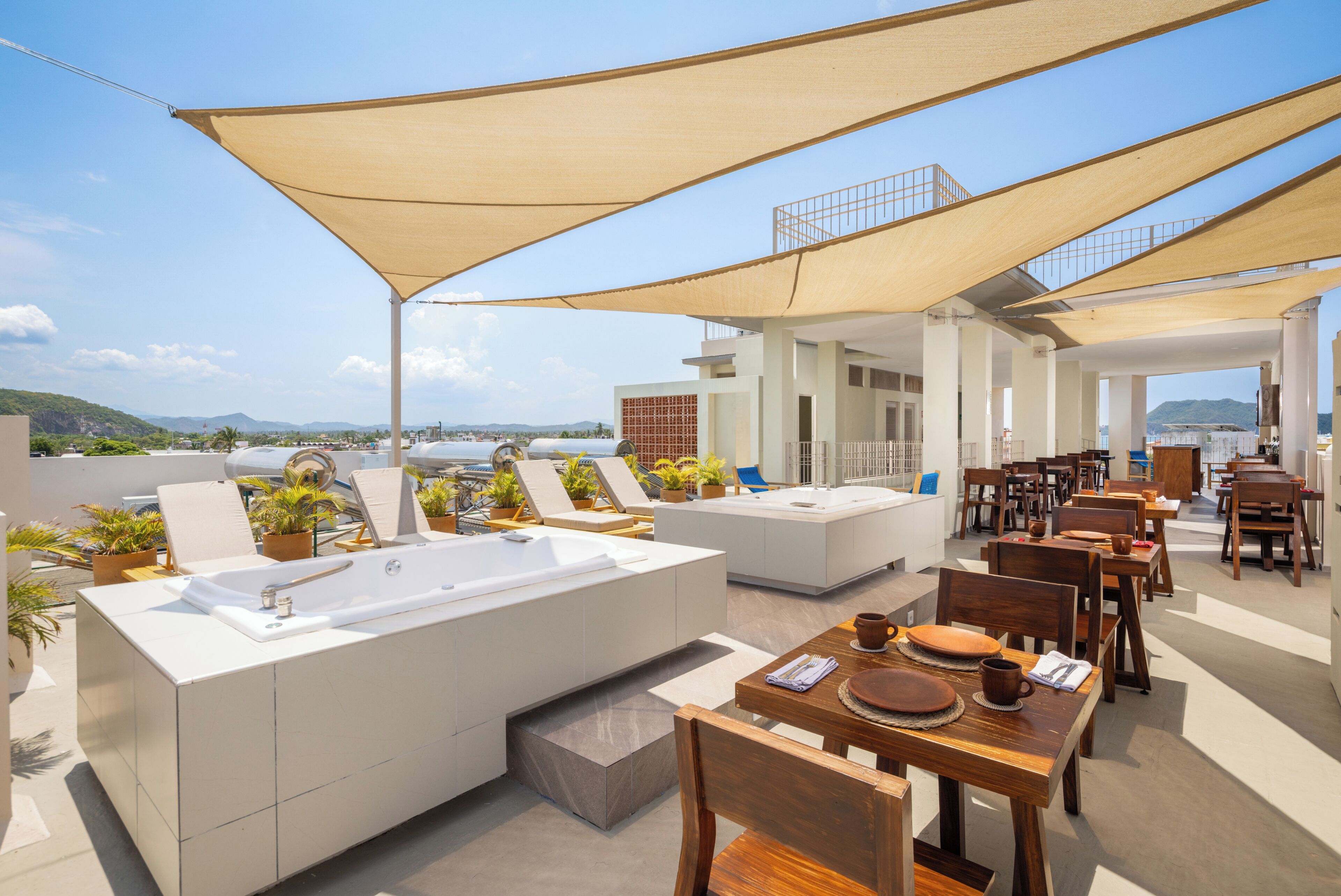 Eine Terrasse im Freien mit einem großen Waschbecken, einer Sitzecke und Esstischen.