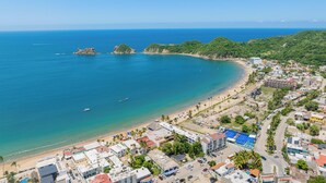 A coastal town with a beach, buildings, and a clear blue sky. - Hotel Tepalcates (San Patricio Melaque)