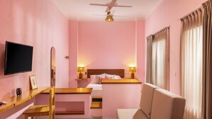 A hotel room with a bed, a desk, a chair, a television, and a ceiling fan. - Hotel Tepalcates (San Patricio Melaque)