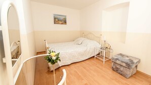 A bedroom with a bed, a bedside table, a lamp, a small stool, and a painting on the wall. - Sunny Elegant Crikvenica Apartments (Crikvenica)