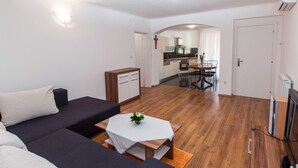 A modern living room with a sofa set, a coffee table, and a kitchen visible through an archway. - Sunny Elegant Crikvenica Apartments (Crikvenica)