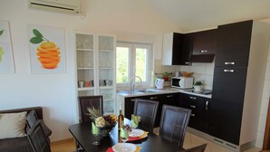 A modern kitchen with dark cabinets, a dining table set with plates, glasses, and a centerpiece. - Seaside Escape Selce Apartments (Crikvenica)