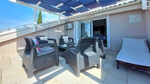 An outdoor patio with wicker furniture, a table, and a covered area with a view of the sky. - Seaside Escape Selce Apartments (Crikvenica)