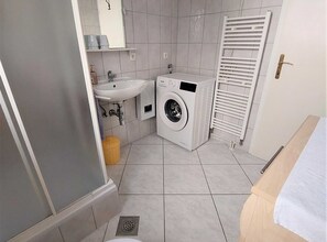 A compact bathroom with a sink, a washing machine, a toilet, and a towel rack. - Elegant Apartments With Sea View and Balcony (Crikvenica)