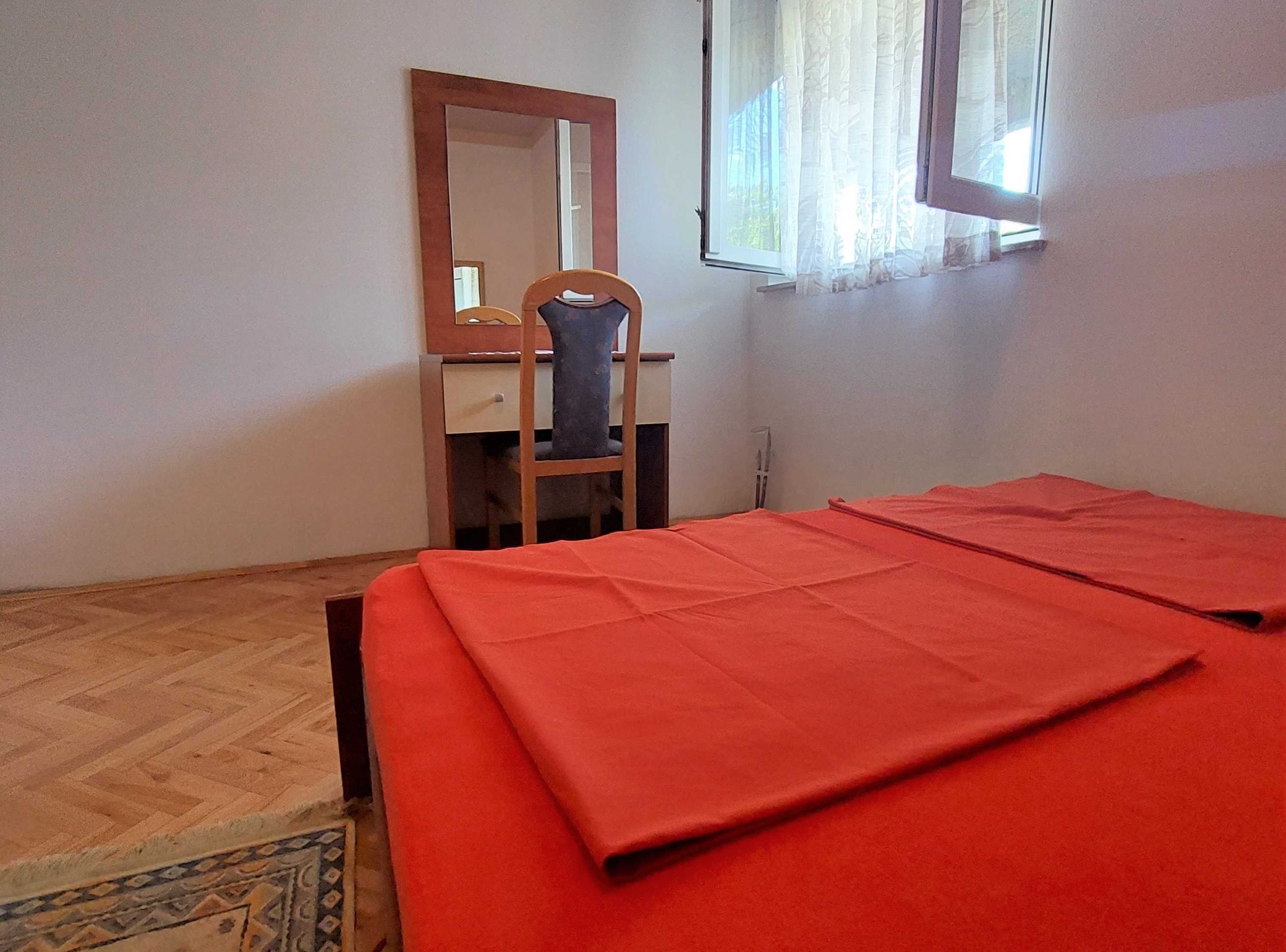 A room with a bed, a desk, a chair, and a window.