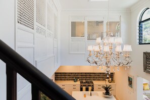 A spacious kitchen with a modern stove, a sink, and a chandelier.