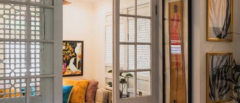 A doorway leading to a living room with a sofa, a rug, and framed artwork on the walls.