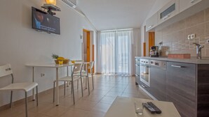 Une cuisine moderne avec un coin repas, un téléviseur fixé au mur et un îlot central doté d’une machine à café.