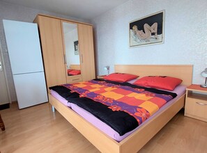 A bedroom with a bed, a wardrobe, a mirror, a nightstand, and a painting on the wall. - Sleek and Serene Rooms Crikvenica (Crikvenica)