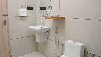 A bathroom with a toilet, sink, and mirror.