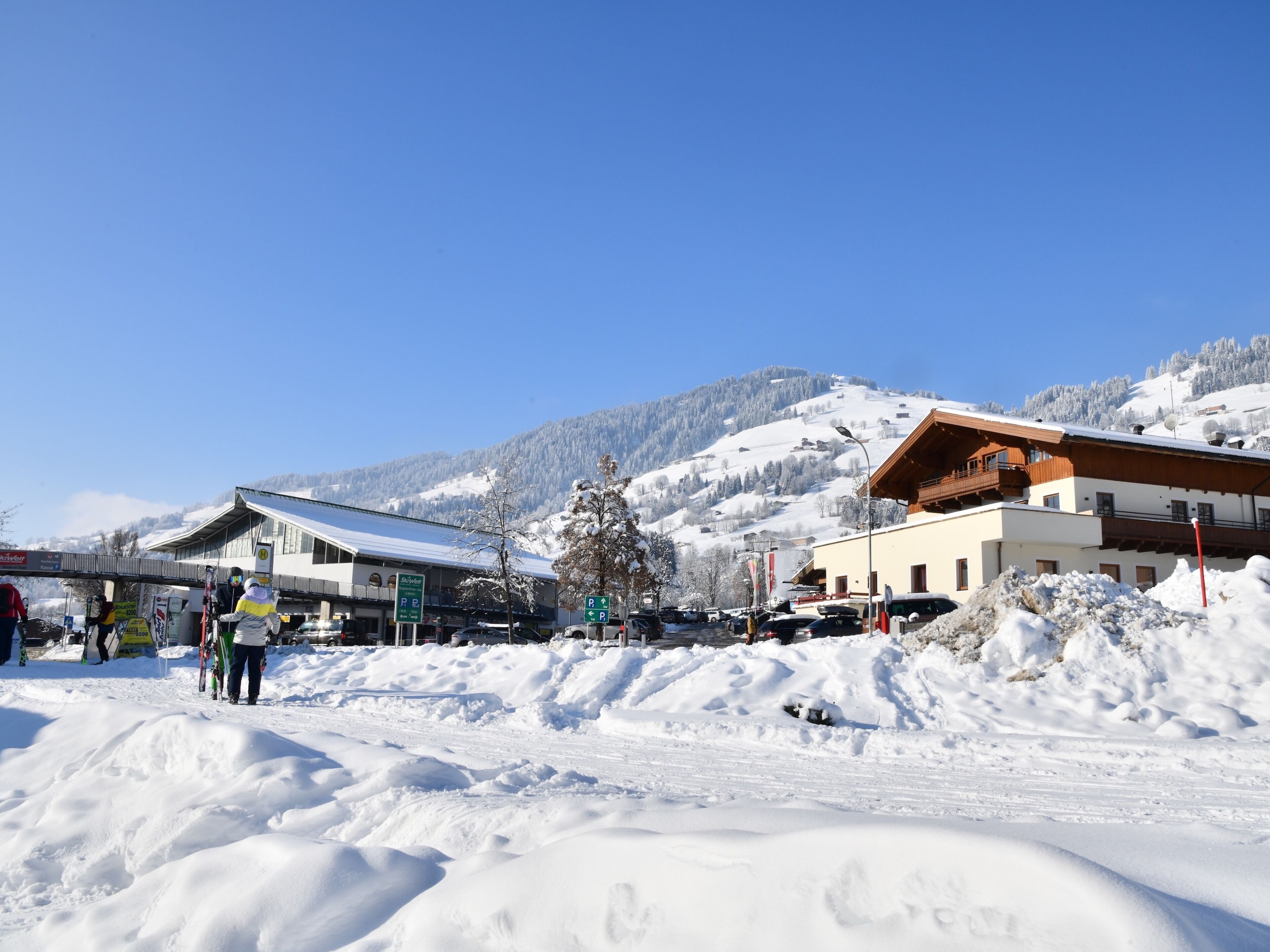 A snow-covered area with buildings, including a hotel with a ski lift in the background.
