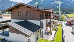 Ein mehrgeschossiges Gebäude mit einem geneigten Dach, Balkonen und Blick auf Berge.