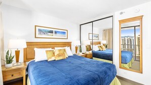 A hotel room with a large bed, two bedside tables, a mirror, and a view of buildings.