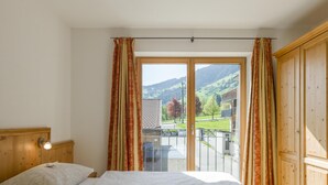 Quarto com duas camas, cabeceira de madeira, mesa de cabeceira e janela com cortinas.