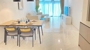 Un comedor moderno con una mesa dispuesta para cuatro personas, un sofá, un televisor y un ventilador de techo.