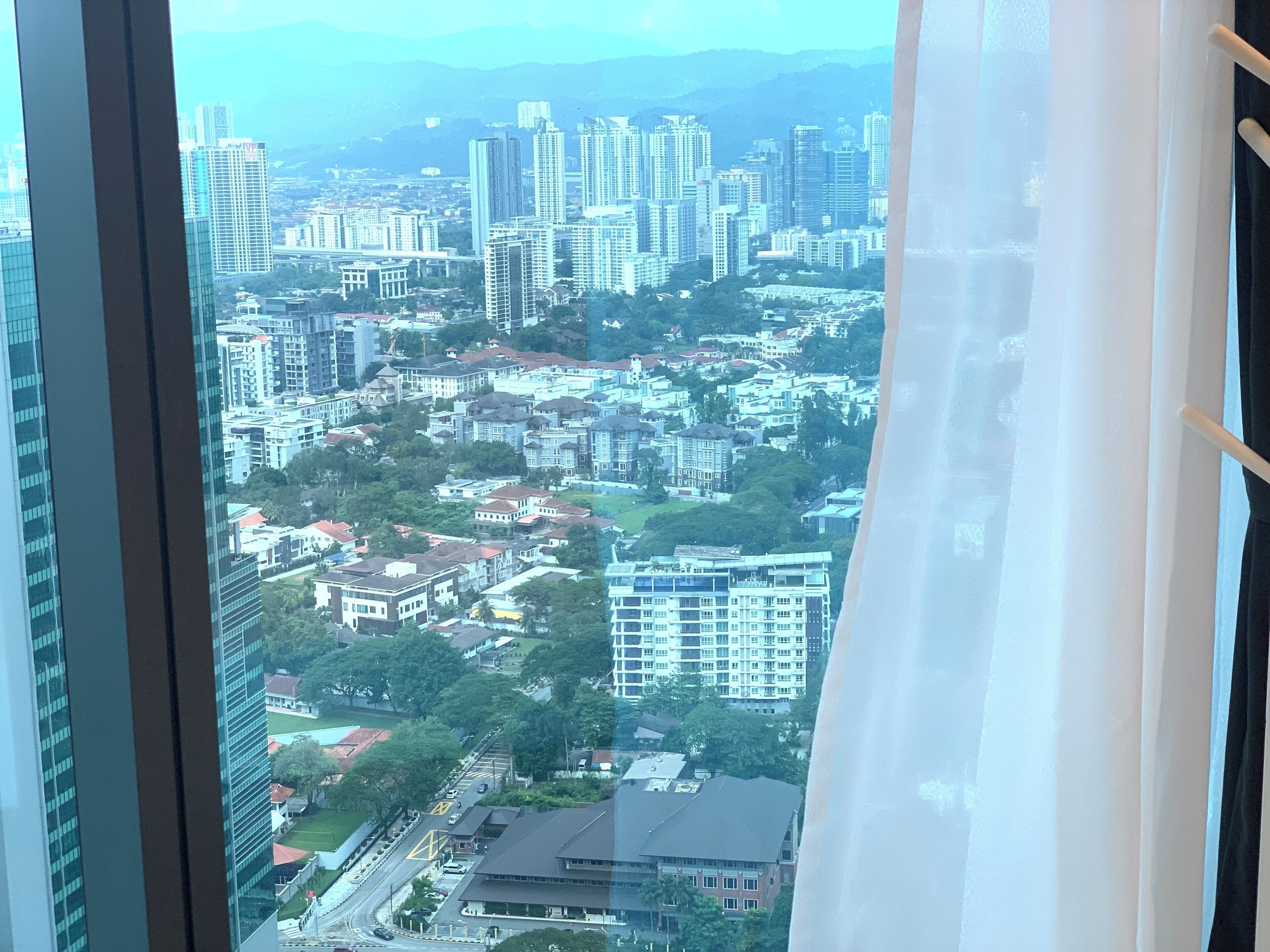 A cityscape through a window with a curtain.