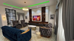 A modern living room with a large flat-screen TV, plush sofas, and a decorative wall unit. - 
3bd waterfront, Rooftops Apartment on Admiralty Lekki-ikoyi w/Pool&Gym (Lekki)