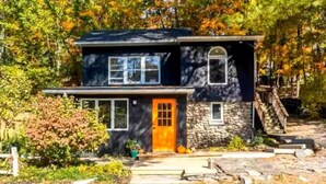 A two-story house with a stone facade, a wooden deck, and a front porch.