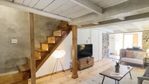 A spacious living area with a wooden staircase, a TV, a sofa, and a coffee table.
